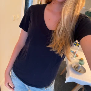 Mörkblå v-ringad t-shirt från Åhléns - Enkel mörkblå  t-shirt från Åhléns med v-ringning och korta ärmar. Skön passform och tillverkad i mjuk bomull, perfekt till jeans eller shorts. Stilren och lätt att matcha med allt i garderoben.