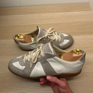 Maison Margiela GATS skor | 42 - Ett par tvärfeta Maison Margiela sneakers i mocka och läder | Skick: 6/10 | Size: 42 | Defekter: Ja, sulan något sliten med ett litet hål (se bild 4 och 5), men inget som en skomakare inte kan fixa | Tillbehör: Nej | Nypris: ca 6000:- | Tveka inte att kontakta mig vid övriga frågor😁!