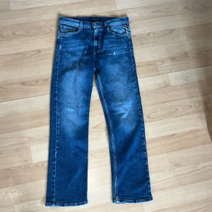 Blå jeans från Replay straight fit storlek 28/32 - Snygga blå jeans från Replay med klassisk femficksdesign och raka ben. Jeansen har en cool tvätt med lätt slitna detaljer och kontrastsömmar. Passformen är straight och materialet är robust denim som ger en skön känsla. Perfekt för dig som gillar en tidlös stil. Priset kan diskuteras.