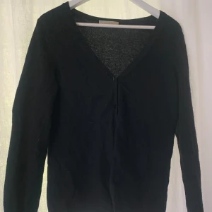 Svart kashmirkofta med v-ringning - Mysig svart kofta i lyxig kashmir med v-ringad hals och knäppning framtill. Säljer pga dålig användning. Pris kan diskuteras!