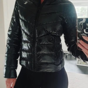 Svart pufferjacka Calvin Klein  - Glansig höst/vinterjacka från Calvin Klein.  Vadderad pufferjacka, något slimmad i modellen.   Storlek XS   Använd fåtal gånger.