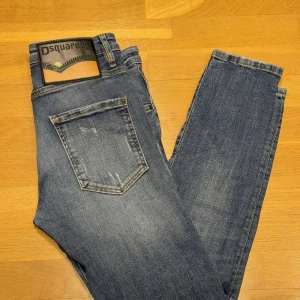 Blå jeans från Dsquared2 - Snygga blå jeans från Dsquared2 med en klassisk femficksdesign. De har en lätt tvättad look med subtila slitningar för en trendig stil. Märkeslogga på baksidan av midjan ger en extra touch. Perfekta för en avslappnad men stilren look.