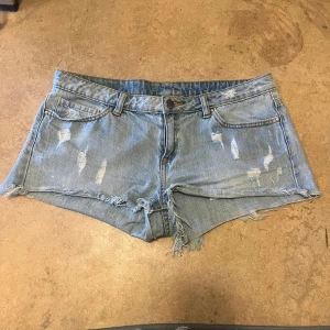 Ljusblå lågmidjade jeansshorts - Lågmidjade jeansshorts från märket never denim med sliten look. Knappt använda och säljer pga för små för mig 🥰  Storlek M 