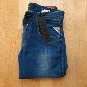 Replay Anbass jeans - Snygga Replay i modellen Anbass. Byxorna är i storlek 30/32. De har en klassisk femficksdesign med en diskret logga på bakfickan. Jeansen har en normal passform och är tillverkade i ett slitstarkt denimtyg. Perfekta för en avslappnad stil. Byxorna är helt nya med tagg men har ett litet hål vid backfickan vilket du kan se på sista bilden. Hålet kan enkelt sys ihop och byxorna kommer se ut som nya. Tveka inte på att komma privat vid minsta fråga!🙌