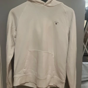 Vit hoodie från GANT - Säljer en stilren vit hoodie från GANT stl 158/164 (13-14 år) Tröjan har en liten logotyp på bröstet och en bekväm huva. 