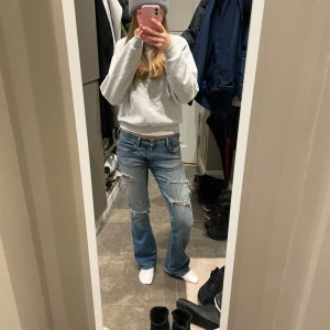 Blå jeans från Diesel - Säljer ett par snygga blå jeans från Diesel med slitna detaljer. Väldigt populär bland ungdomar. Jeansen har en bootcut-stil och är perfekta för en avslappnad look. Märkesdetaljer syns på den lilla fickan framtill.