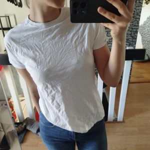 Vit t-shirt - Säljer en klassisk vit t-shirt med rund hals och korta ärmar. Perfekt basplagg för alla tillfällen. Passar bra till jeans eller under en jacka.