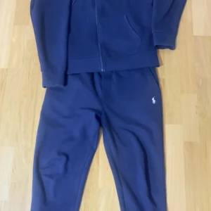 Mörkblå hoodie från Polo Ralph Lauren - Säljer en stilren mörkblå hoodie från Polo Ralph Lauren med dragkedja och det klassiska logotypbroderiet på bröstet. Perfekt för en avslappnad look. Hoodien har långa ärmar och en praktisk huva med dragsko.