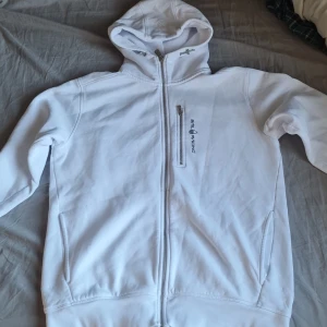Vit hoodie från Sail Racing - Säljer en stilren vit hoodie från Sail Racing. Den har en dragkedja framtill och en broderad logga på bröstet. Perfekt för en avslappnad stil. Huvan ger extra komfort och värme. Använt 3 gånger.                    Priset är diskuterbart!!