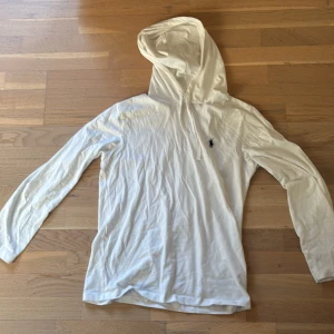 Vit hoodie från Ralph Lauren - Säljer en stilren och HELT OANVÄND vit hoodie från Ralph Lauren med det klassiska broderade logotypen på bröstet. Tröjan har långa ärmar och en bekväm huva med dragsko. Perfekt för en avslappnad look och speciellt perfekt nu till våren då den är lite tunnare. Priset är inte hugget i stenen.