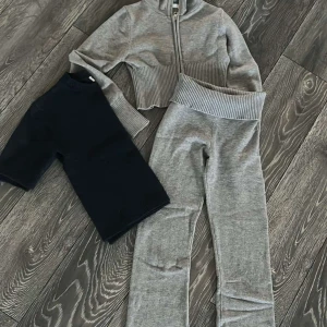 Klädsel 146/152 - Säljer en grå croppad kofta med dragkedja och ribbade detaljer. Matchande byxor. Från Gina Tricot. Stickad kofta från Kappahl 