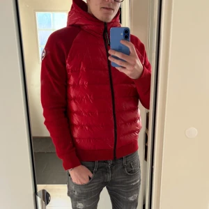 Canada goose - Säljer en snygg röd canada goose jacka med huva och dragkedja. Passar perfekt för höst, vår och varmare vinter dagar och kallare sommardagar, Storlek S passarS/M. såklart äkta, digitalt kvitto finns. nyckick, hör av er vid frågor!