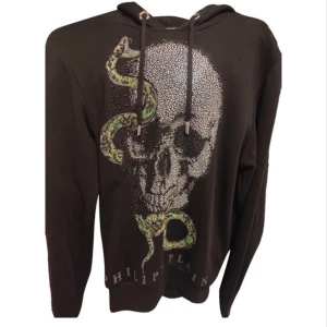 Svart Philipp Plein hoodie - Snygg svart hoodie från Philipp Plein med en iögonfallande dödskalle och orm-design i glittrande detaljer. Hoodien har en justerbar huva med dragsko och är perfekt för en cool och edgy stil.
