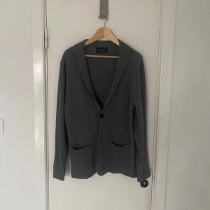 Grå stickad kavaj från Zara Man - Snygg grå stickad kavaj från Zara Man med två knappar och praktiska fickor framtill. Perfekt för en stilren look. Kavajen har en klassisk krage och är långärmad. Dessutom i ett riktigt skönt material. Skriv om ni har några övriga frågor🙌