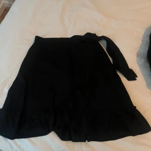 Svart kjol från Gina Tricot - Snygg svart kjol från Gina Tricot i storlek XS. Kjolen har en volangdetalj vid fållen och är perfekt för en stilren look. Den är enkel att matcha med olika toppar och accessoarer.