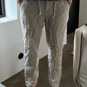 Zara  linnebyxor - Säljer ett par beiga linnebyxor med dragsko i midjan och raka ben. Byxorna har en avslappnad passform och är perfekta för varmare dagar. Defekt på andra bilden 