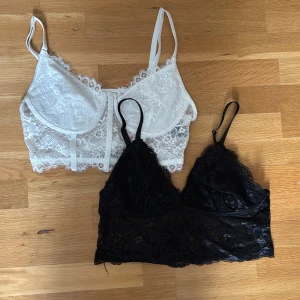 Två spets toppar - Säljer två snygga toppar, en i vit spets och en i svart spets. Båda har tunna axelband och vacker spetsdetalj över hela toppen. 