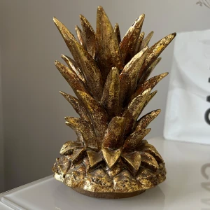 Dekorativ ananas i guld - Guldig ananas som har varit till ett lock till en vas som tyvärr har gått sönder. Men jag har haft ananasen som dekoration och är jättefin och ha framme som den är
