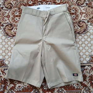 Beiga shorts från Dickies med loose fit - Klassiska beiga shorts från Dickies med loose fit och längre ben. Modellen har dragkedja och knapp framtill, samt sidofickor och bakfickor. Perfekta för en avslappnad stil under varmare dagar.