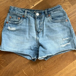 Levis jeans shorts - Blå jeansshorts från Levis med hål. De är små i storlek.