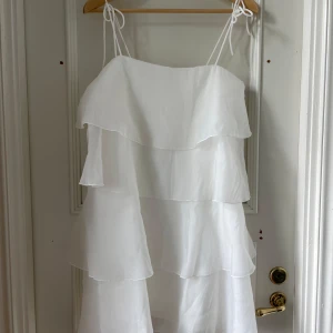 Vit volangklänning från Gina Tricot - Säljer en superfin vit klänning från Gina Tricot i storlek 36 men passar även 38. Klänningen har tunna axelband och flera lager volanger som ger en luftig och somrig känsla. Perfekt för varma dagar eller studenten!!! 💕🎉 Aldrig använd. 
