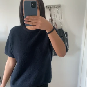 Mörkblå stickad tröja - Mysig mörkblå stickad tröja med rund hals och korta ärmar. Perfekt för lager-på-lager och enkel att matcha med olika outfits. Snygg och stilren design som passar till många tillfällen.