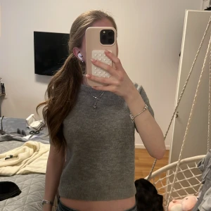 Grå stickad kortärmad tröja från ZARA - Säljer en grå stickad kortärmad tröja från ZARA. Tröjan har rund halsringning och ribbade kanter. Köpt för 400kr.