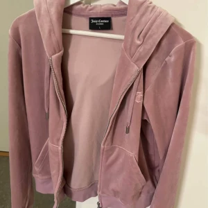 Rosa velour hoodie från Juicy Couture - Hoodie från Juicy Couture. Som ny, inga fläckar och superfint skick. Fick i present men inte min favoritfärg direkt. En av metallbitarna på snörerna har lossnat i tvättmaskinen, men denna går enkelt att limma tillbaka med superlim. Därav prissänkningen. 