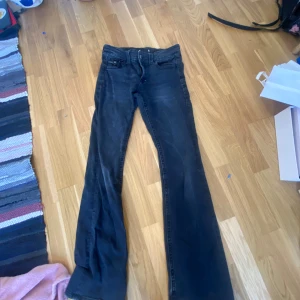 Svarta bootcut jeans - Svarta jeans med bootcut passform och klassiska fem fickor. Byxorna har dragkedja och knapp framtill samt markerade sömmar. Perfekta för en avslappnad och trendig look.