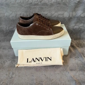 Bruna sneakers från Lanvin i mocka - Säljer ett par bruna sneakers från Lanvin. Storlek uk 7 vilket motsvarar 42. Inget og kommer med i köpet(kvitto box, påse) endast skorna. Priset är ej hugget i sten. 