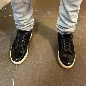 Svarta lanvins (byten) - Snygga svarta sneakers med blanka detaljer och vit platt sula. Skorna har snörning och en klassisk rund tå. Perfekta för en stilren och avslappnad look. (Helst byten)