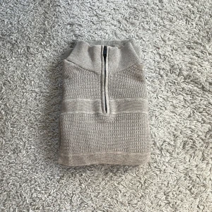 Beige stickad tröja med dragkedja från Dressmann - Säljer en beige stickad tröja från Dressmann i storlek M. Tröjan har halv dragkedja framtill och hög krage. Den är ribbstickad med diskreta ränder och passar perfekt till kyligare dagar. Säljer då den är för liten. Använd ca 2 gånger.