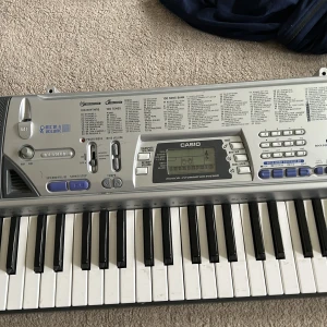 Casio CTK-496 Keyboard - Säljer ett Casio CTK-496 keyboard med 100 låtar, 100 rytmer och 100 toner. Tangentbordet är silverfärgat med svarta och vita tangenter, inbyggda högtalare och digital display. Perfekt för både nybörjare och mer erfarna musiker.