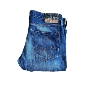 Replay Waitom jeans - Snygga Replay Waitom jeans i klassisk blå tvätt med raka ben och normal passform. Jeansen har fem fickor, tydliga slitningar och coola detaljer på bakfickorna. Tillverkade i slitstarkt bomullstyg, perfekta för en avslappnad streetstil. Midja 45cm . Jag skickar ej bild när jag bär plaggen och jag vet ej vilken längd och vikt de passar då jag inte prövar kläderna jag säljer 😃