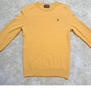 Gul stickad tröja Morris Stockholm - Snygg gul stickad tröja från Morris Stockholm med rund halsringning och diskret logga broderad på bröstet. Tröjan har lång ärm och klassisk passform, perfekt för lager-på-lager-stil under kyliga dagar.