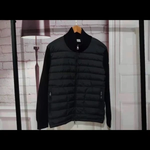 Moncler Cardigan - Säljer en  Moncler cardigan i svart med klassisk dunpanel fram. Modellen är stilren och passar perfekt året runt.