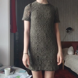 Beige spetsklänning med dragkedja - Supersnygg beige kortklänning med vackert spetsmönster och korta ärmar. Klänningen har rund halsringning och en synlig dragkedja i guld baktill. Fodrad insida för extra komfort. Perfekt för dig som gillar romantisk och trendig stil.