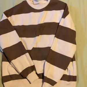 Randig tröja från Pull&Bear XS - Säljer en tröja från Pull&Bear i storlek XS. Tröjan har breda bruna och vita ränder, rund halsringning och långa ärmar. Perfekt för dig som gillar en chill och avslappnad stil.