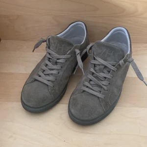 Grå mockasneakers från Selected Homme - Snygga sneakers i grå mocka från Selected Homme. platt sula och klassisk snörning. Perfekta för dig som gillar stilrena och enkla sneakers med en modern touch.