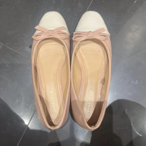 Ballerinaskor i ljusrosa/beige och vitt från Anna Field - Snygga ballerinaskor från Anna Field i beige lack med vit tå och söt rosett framtill. Skorna har en klassisk rund tå och platt sula, perfekt för en chic och feminin look. Materialet är glansigt syntet som ger en elegant finish. defekterna syns på sista bilden och det syns inte från långt håll!💋💋 har använt dom här 3 gånger så dom är ganska nya!! köptes för 280kr och säljs för 200kr