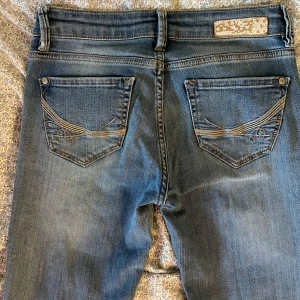 Vintage-jeans från Mexx - Ljusblå jeans från Mexx med broderade detaljer på fickorna. Fint skick. Passform: straight, low waist. Storlek: W27, L30