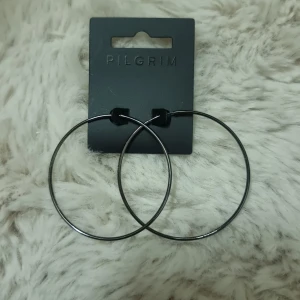 Stora Pilgrim hoops - Snygga stora hoops från Pilgrim i mörk grafitgrå. Ca 5,5 cm i diameter. Nya med originalförpackning. " öronkontaktytan" gjord av 316L kirurgiskt stål.