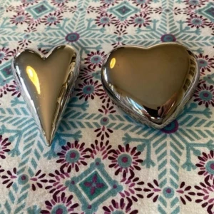 Silvriga hjärtan! Fin inredningsdetalj!  - Jättefina! Har bara legat i skåp. Aldrig ”använt”.   Det långa väger 40 gram  8,5 cm långt  5 cm brett   Det korta väger 60 gram  6,5 cm brett  7 cm långt   50 kr för bägge.  Vet ej märke eller material