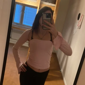 Ljusrosa långärmad offshoulder topp - Säljer en ljusrosa långärmad topp med offshoulder-design och croppad passform. Toppen har en enkel och stilren look, perfekt att styla med jeans eller kjol. Mjuk och stretchig känsla för en bekväm vibe.