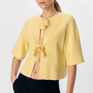 STICKAD KOFTA  - Oanvänd stickad kofta med rosetter på framsidan i modellen Topp objUlla Parvi 2/4 Knit Cardigan från märket Object. Storlek M. Nypris 599kr. Går att ha den både fram och bak. 