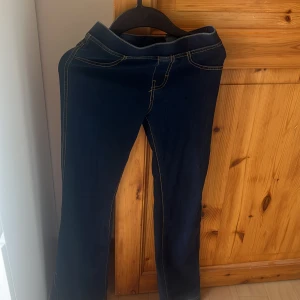 Mörkblå jeansbyxor från H&M - Snygga mörkblå jeansbyxor från H&M med kontrastsömmar och klassisk femficksdesign. Byxorna har rak passform och normal midja, perfekta till sneakers eller boots. Materialet är mjukt och stretchigt för extra komfort.
