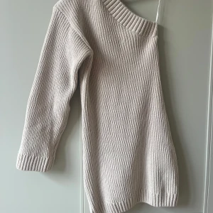 Ribbstickad offshoulderklänning - Säljer en beige ribbstickad klänning med offshoulder-design. Klänningen har lång ärm och bred ribbad kant vid halsen. 