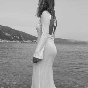 Vit långklänning med öppen rygg - Supersnygg vit långklänning med öppen rygg och snörning i ryggen. Klänningen har långa ärmar och är figurnära med lätt glansigt material. Perfekt för sommarens alla tillfällen både på fest å på beachen🌟