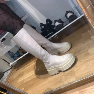 Chunky vita stövlar med platåsula - Säljer ett par höga chunky stövlar i vitt med grov platåsula från Bershka.  Perfekta för att ge din outfit en edgy vibe. 