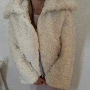 Beige teddyjacka - En mysig och varm beige teddyjacka med dragkedja. Jackan har en fluffig textur och är perfekt för kyliga dagar. Från H&M i storlek XS
